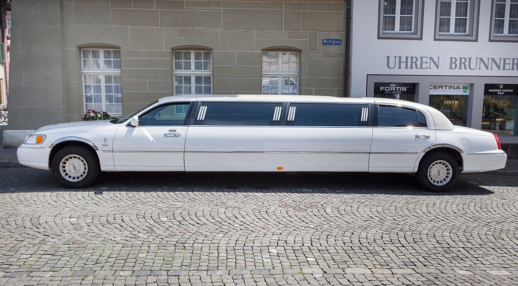 Elegant white limousine waiting in front of a luxury venue.