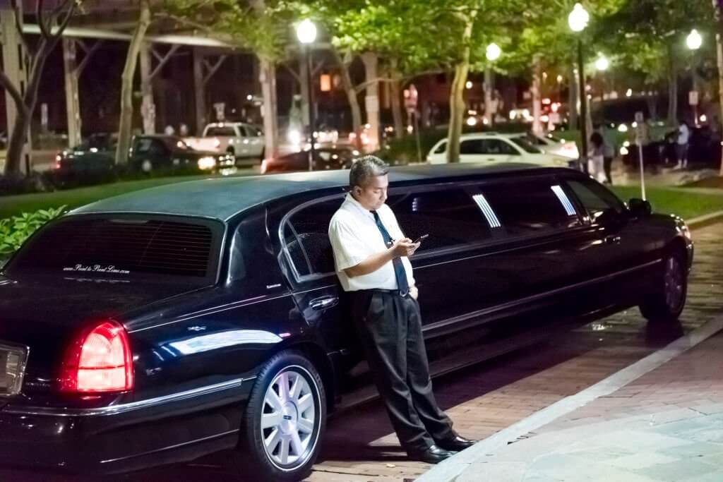 Limo limousine driver standing by car sidewalk