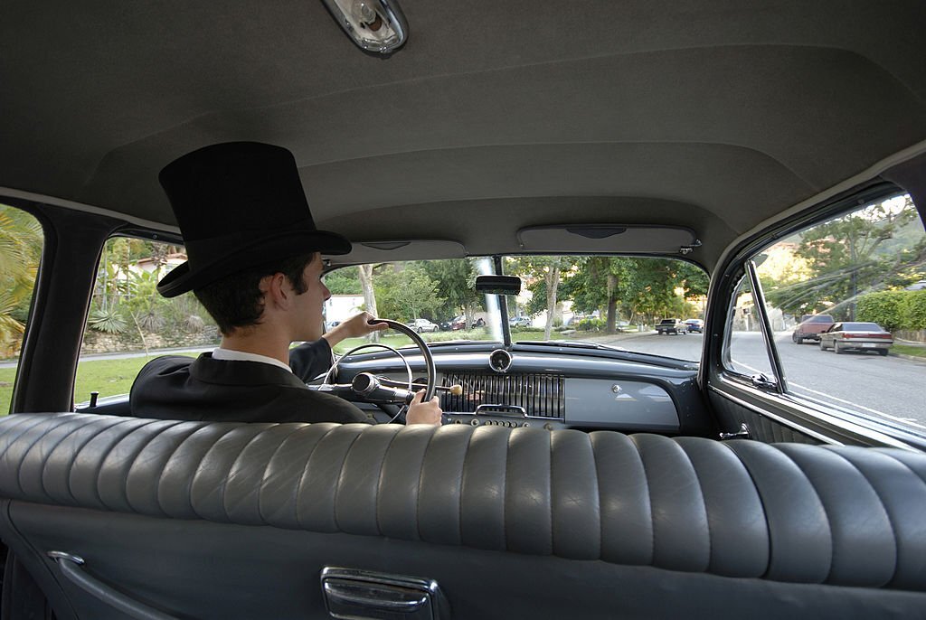 A young driver with top hat driving away. 