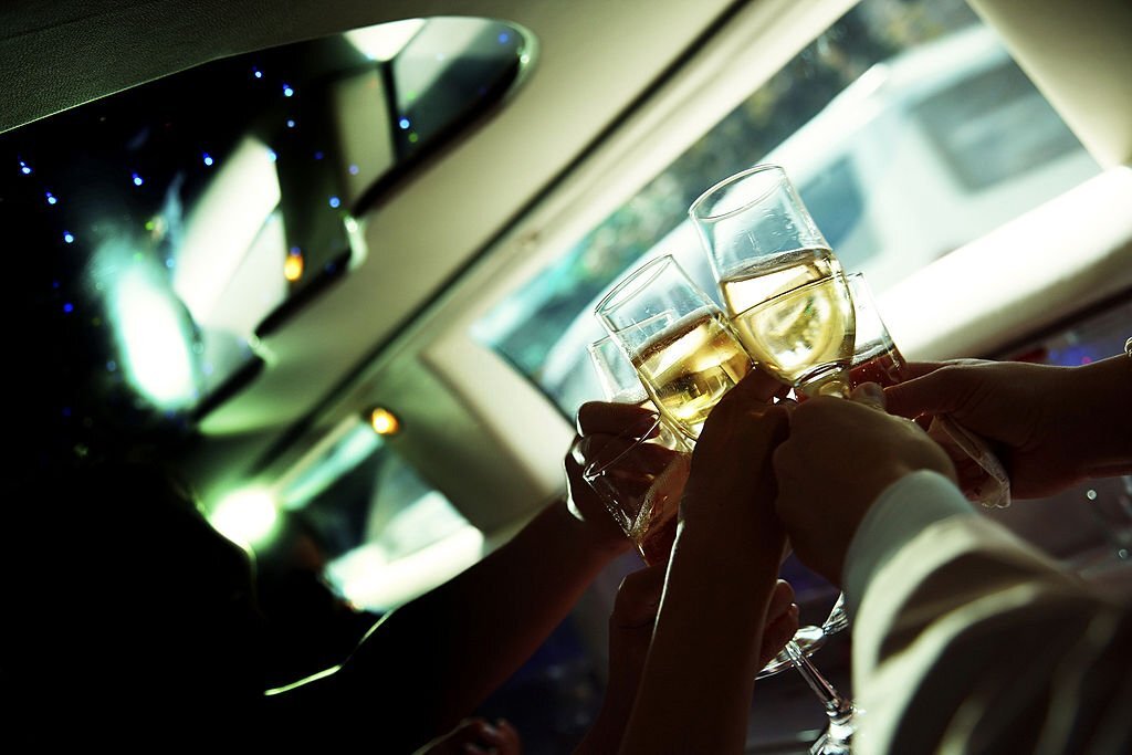 photo of the human hand holding wine glasses in limousine