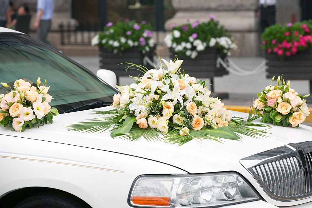 A luxurious white limousine adorned with ribbons and flowers
