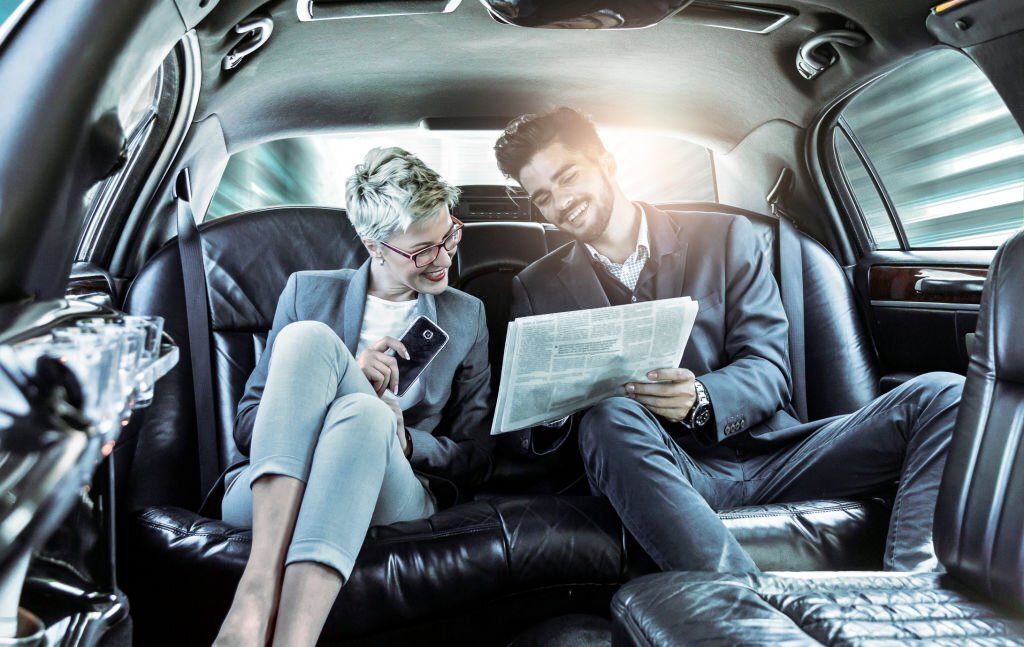 Businesswoman and businessman enjoying limo ride