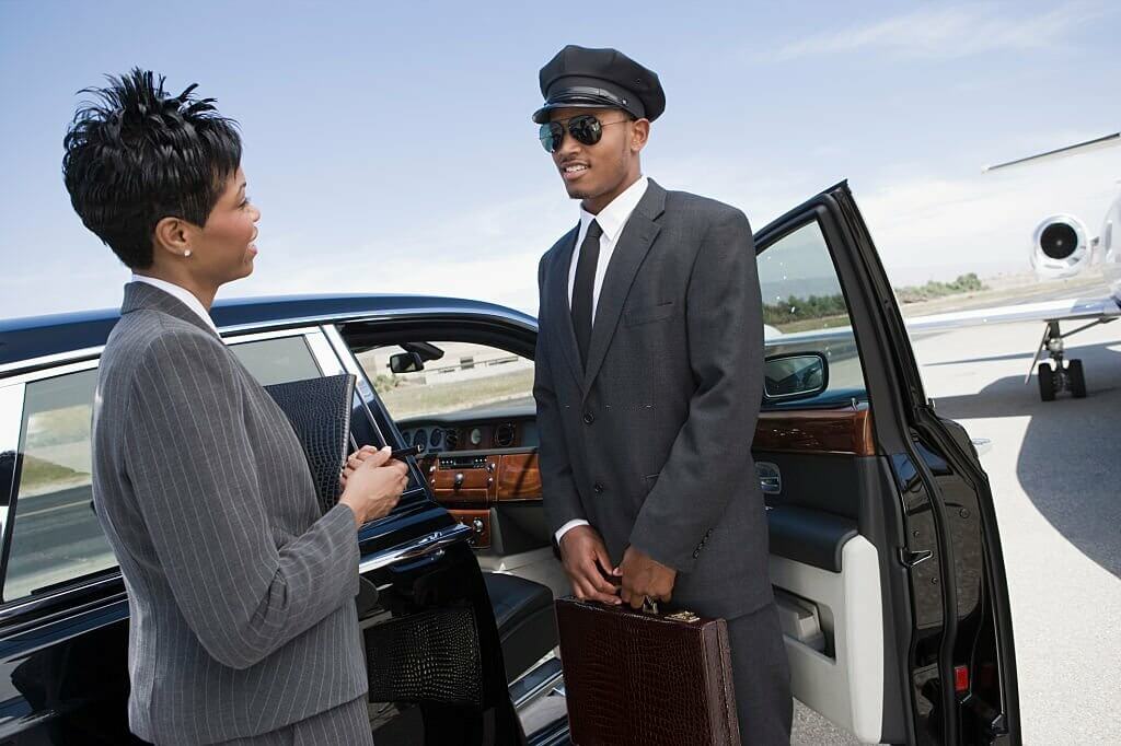 chauffeur standing in front of limousine and talking.