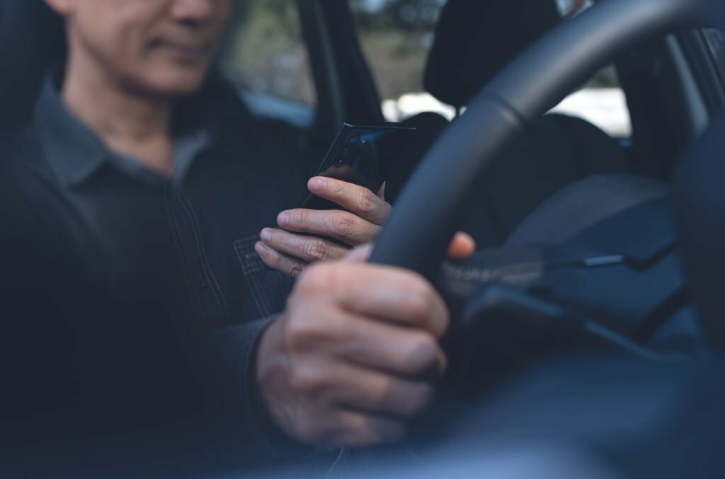 driver using mobile smart phone inside a car