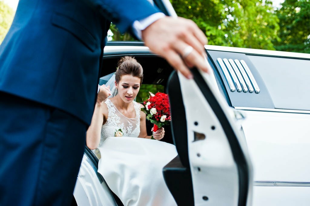 Groom open door of limousine and take hand to bride.