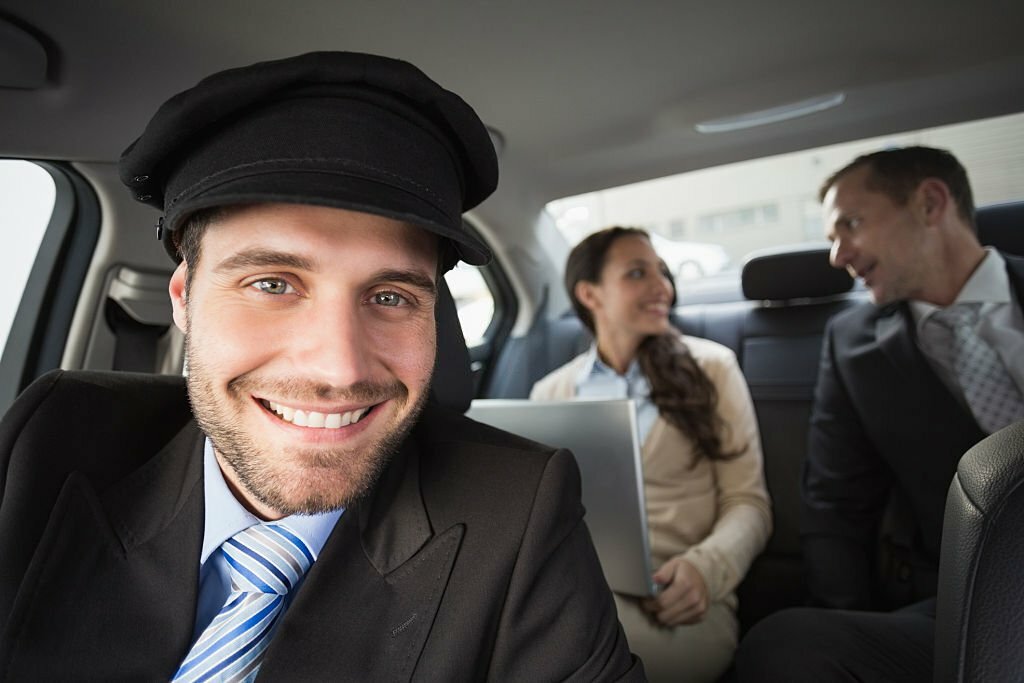 Handsome chauffeur smiling at camera in the car.