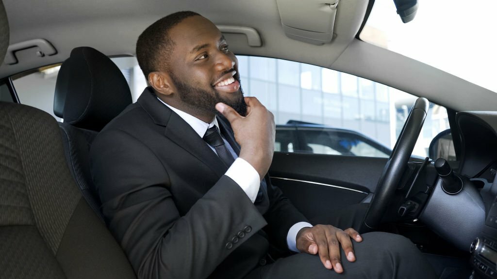 American businessman looking in rear-view car mirror.